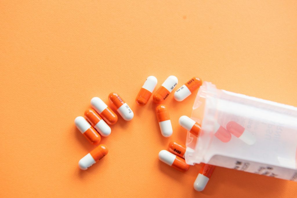 Orange and white capsules spilling from a container